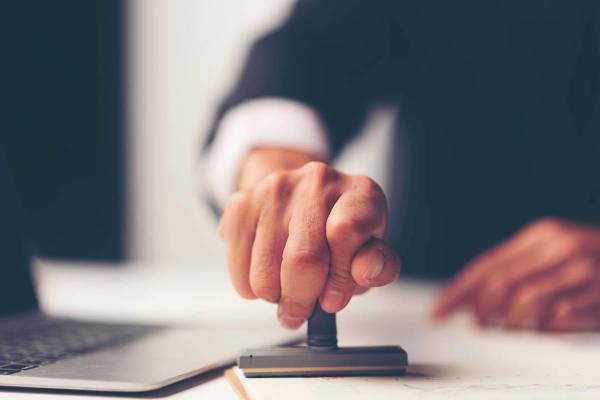 Hand holding a stamp over documents.